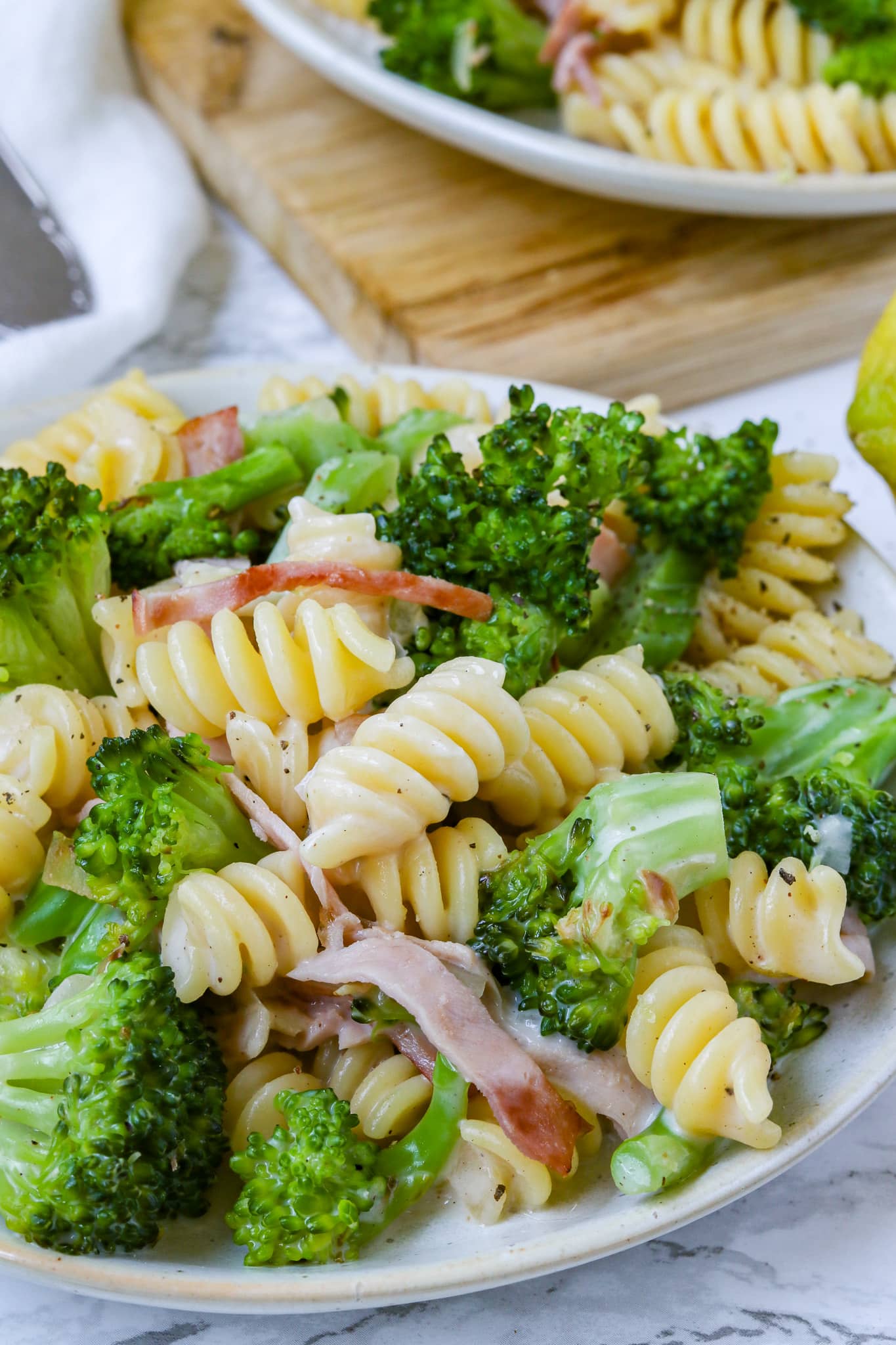 Pasta mit Brokkoli und Schinken, Nahaufnahme, serviert auf einem beigen Teller auf hellem Hintergrund