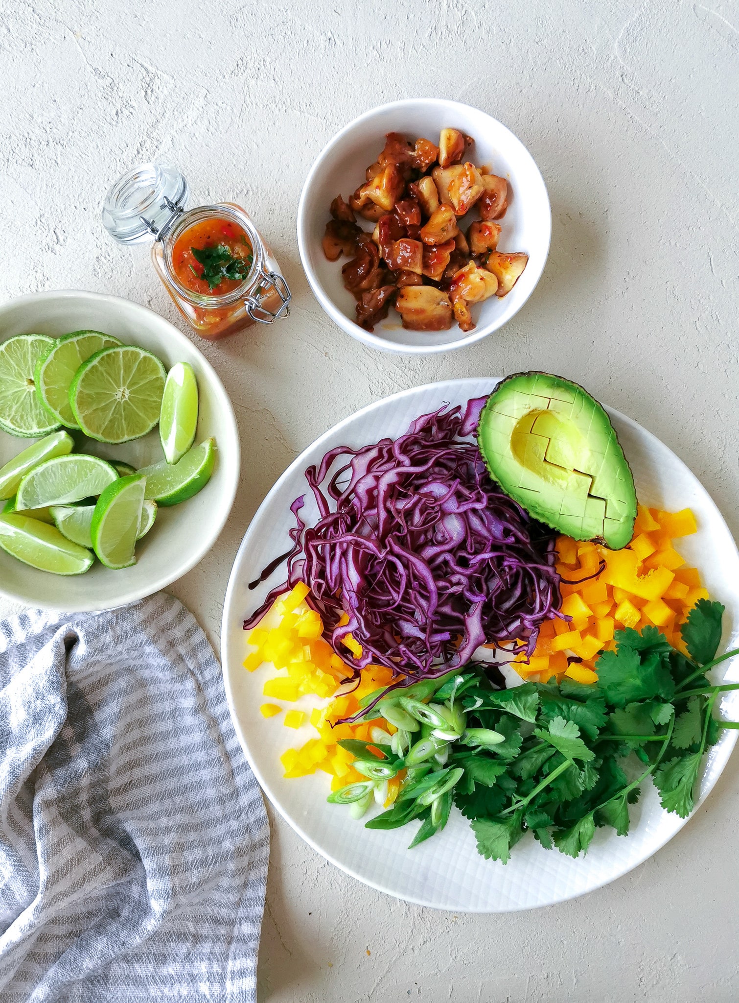 Fruchtig-scharfe Tacos, das rohe Gemüse ist geschnitte auf einem weißen Teller liegen Rotkohlstreifen, Paprikawürfel, frischer Koriander