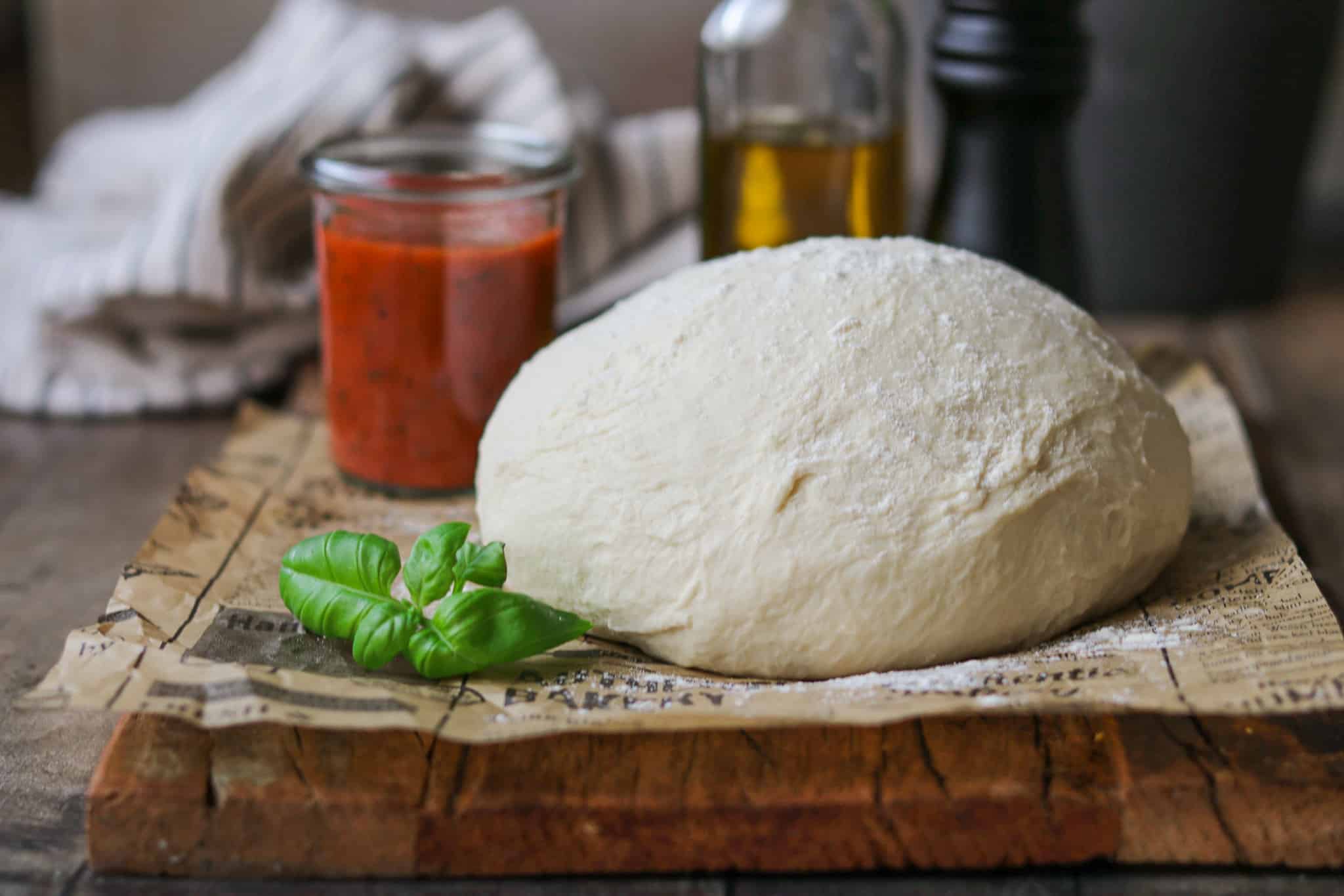 Pizzateig  selber machen – einfaches Rezept, großer leckerer Teig auf einem rustikalen Holzbrett