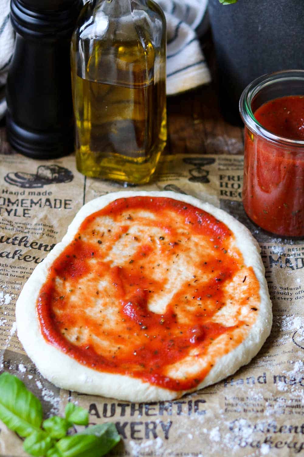 Pizzateig  selber machen – einfaches Rezept, Ausgerollter runder Teig mit frischer Tomatensoße