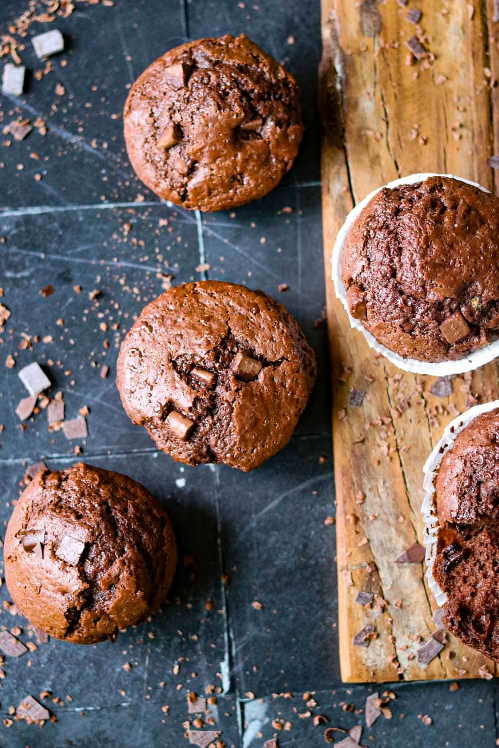 double chocolate muffins, zwei auf brett- drei auf einem dunklen untergrnd