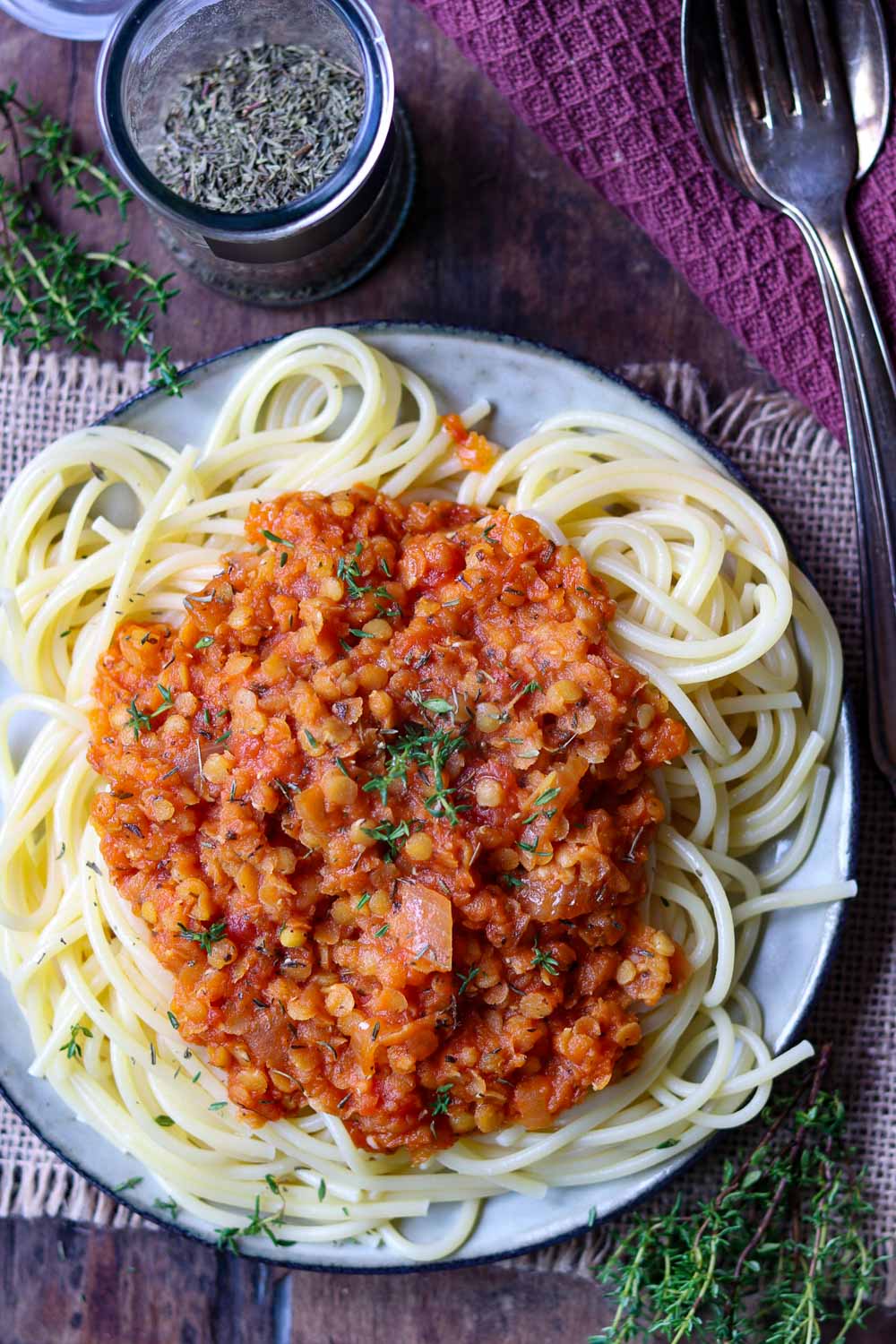 Spaghetti mit Linsenbolognese serviert auf einem Holzbrett