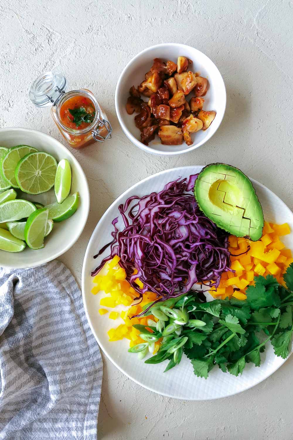 Fruchtig-scharfe Tacos, das rohe Gemüse ist geschnitte auf einem weißen Teller liegen Rotkohlstreifen, Paprikawürfel, frischer Koriander