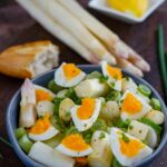 Spargelsalat mit Ei und Senf-Dressing serviert mit Frühligszwiebeln und Baguette
