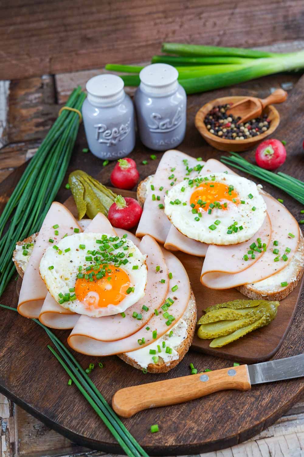 Strammer Max kalorienarm serviert auf Holzbrett mit Schnittlauch und wachsweichem Ei