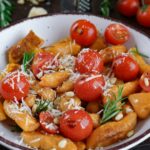 Süßkartoffel Gnocchi Pfanne mit kirschtomaten, pinienkernen und parmesan auf hellem teller