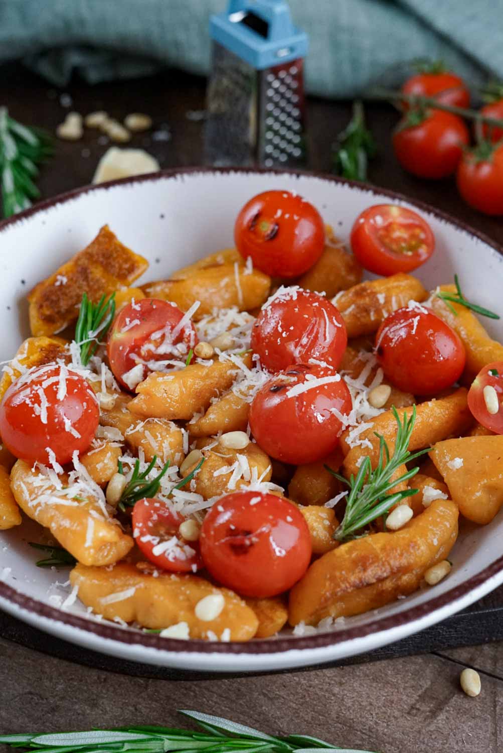 Süßkartoffel Gnocchi Pfanne mit kirschtomaten, pinienkernen und parmesan auf hellem teller